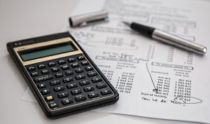 calculator and pen on top of financial documents
